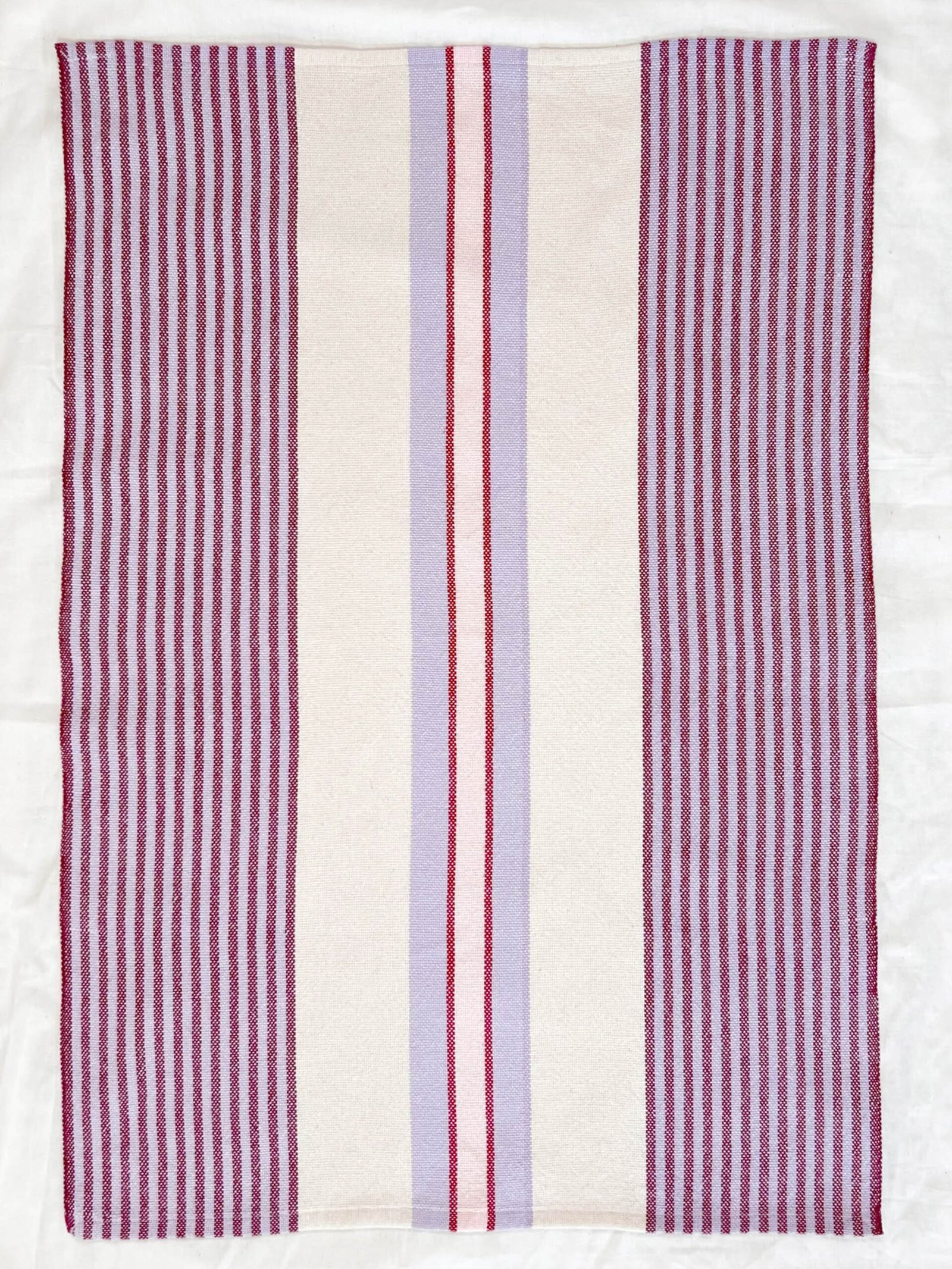 striped tea towel shown flat in pinks, purples, and white