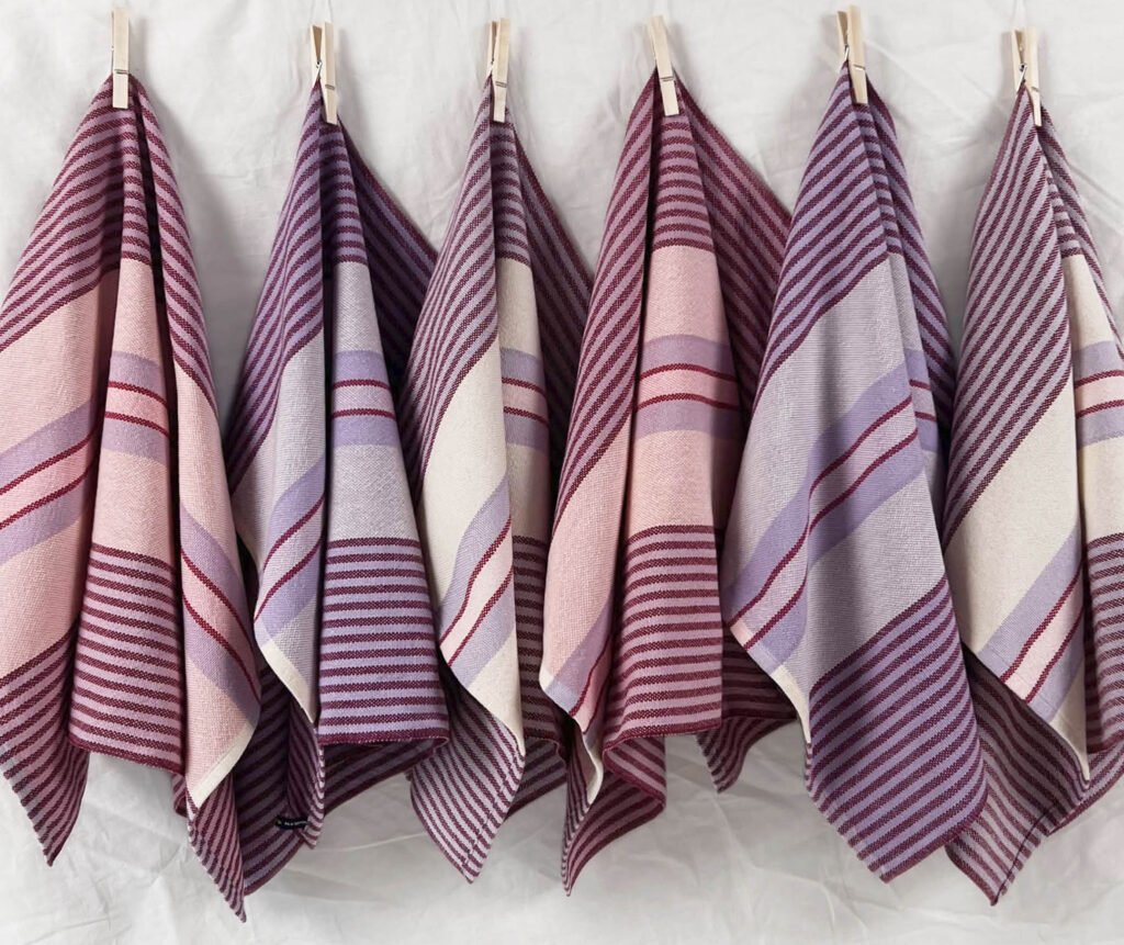 striped tea towels in pinks, purples, and white, hanging in a row