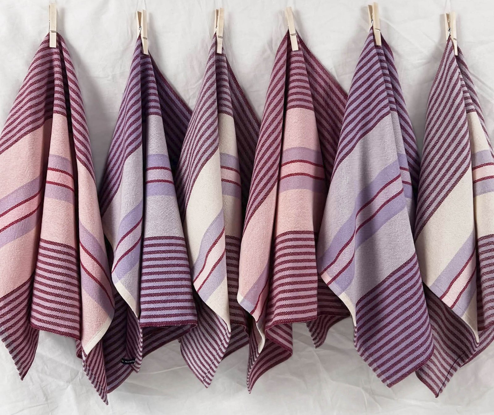 striped tea towels in pinks, purples, and white, hanging in a row