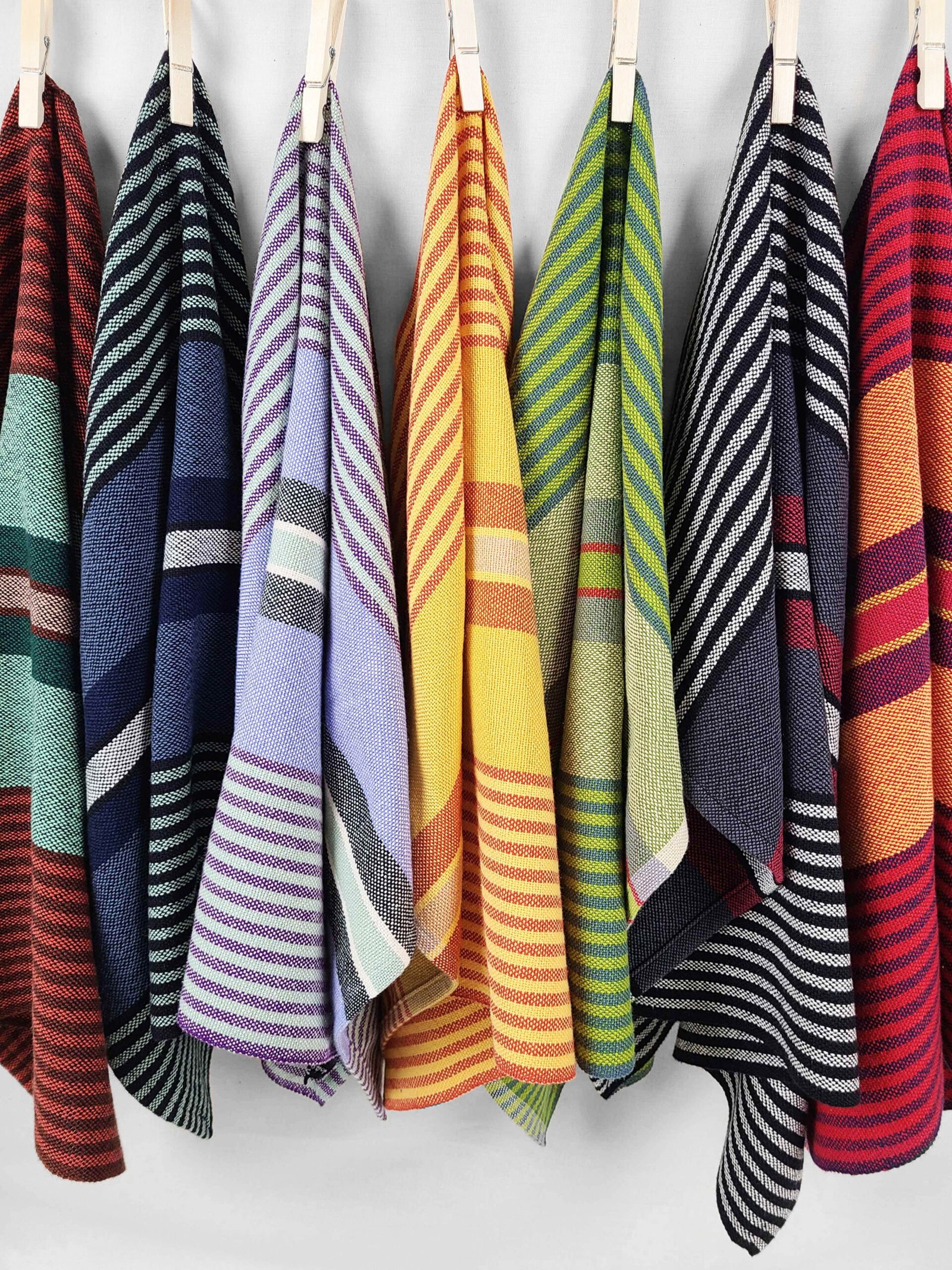 A row of hanging tea towels in different bright colors and stripes