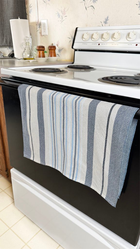 grey and blue stripe towel hanging on oven handle