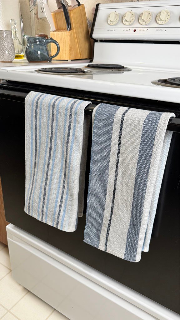 gray and blue towels hanging on a stove handle