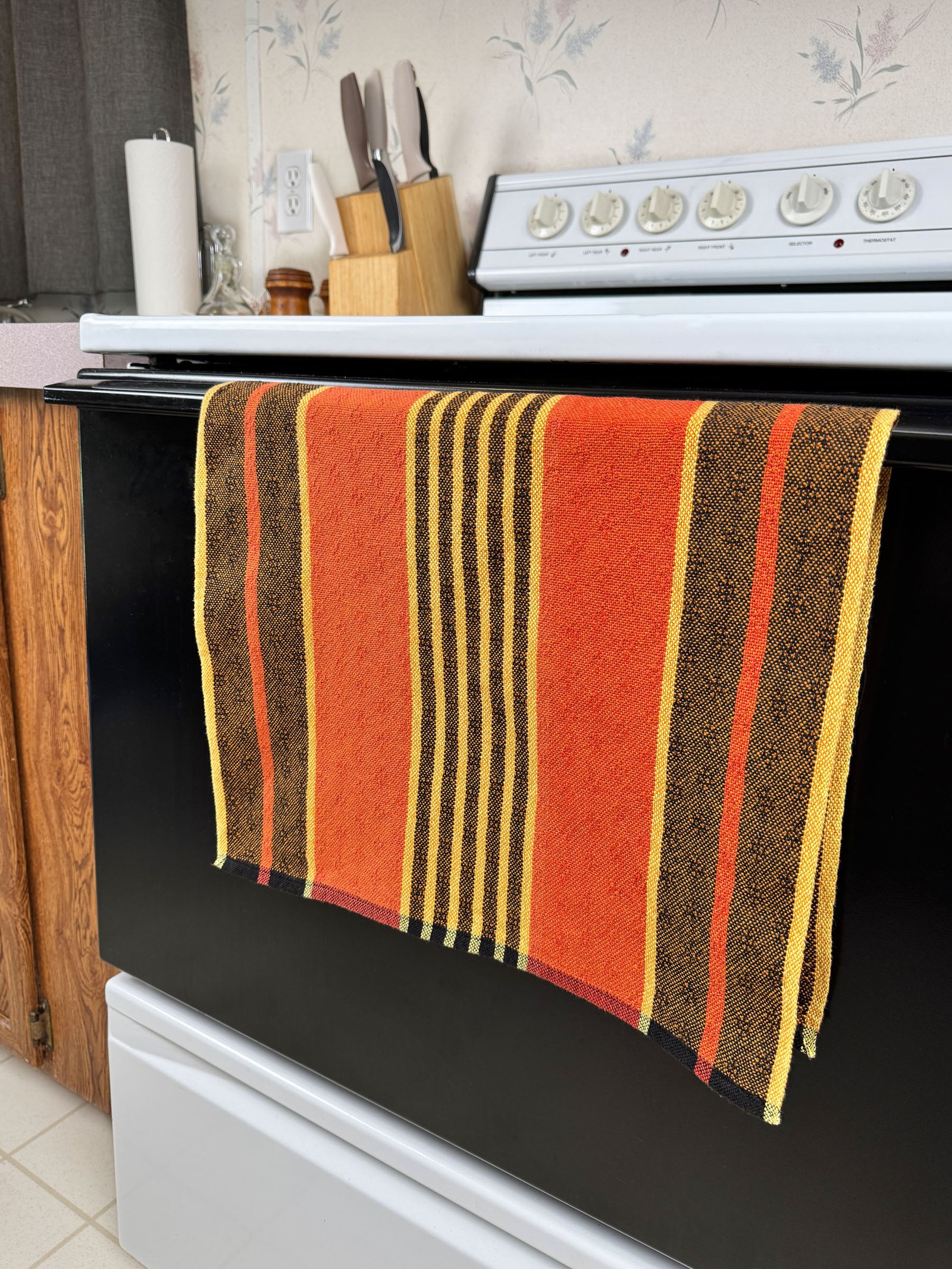 striped halloween tea towel hanging on an oven door